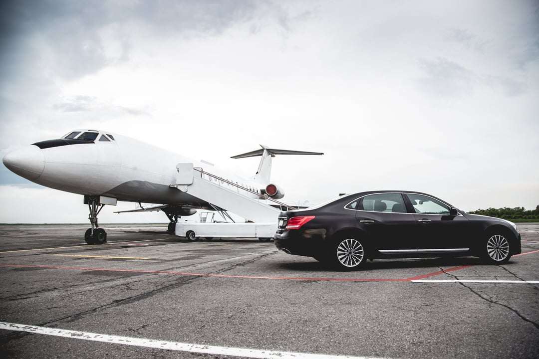 Luxury black sedan parked beside a private jet on the tarmac, symbolizing efficiency, flexibility, and premium service in business aviation.