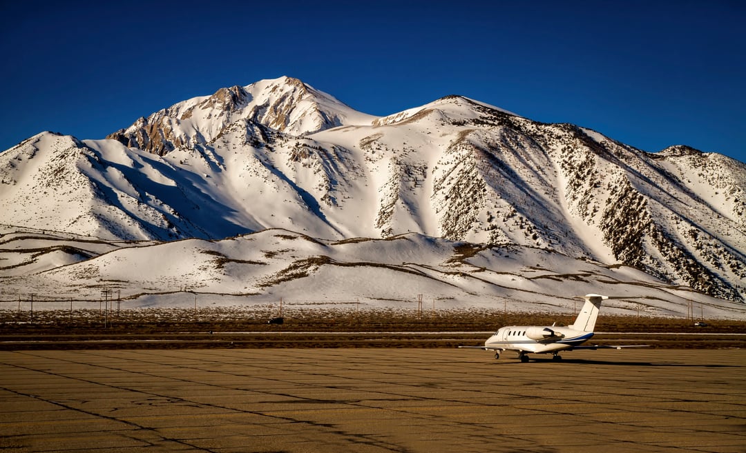 Private jet parked at a mountain airport with snow-covered peaks in the background.